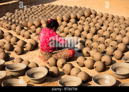 Nepal, Kathmandu Tal, Bhaktapur, Potter's Square, Frau schlichten thown Töpfe trocknen in der Sonne vor dem Feuern im Brennofen Stockfoto