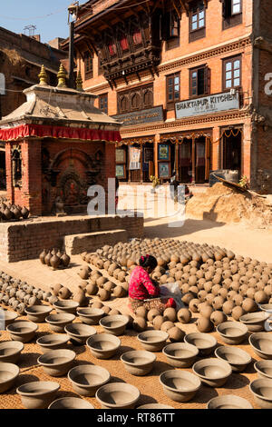 Nepal, Kathmandu Tal, Bhaktapur, Potter's Square, Frau schlichten thown Töpfe trocknen in der Sonne neben Hindu Schrein, vor dem Brennen im Ofen Stockfoto