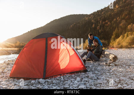 Reifes Paar camping am Flußufer im Abendlicht Stockfoto
