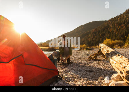 Reife Frau camping am Flußufer, das Sammeln von Holz für das Lagerfeuer Stockfoto