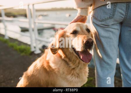 Nahaufnahme der Frau mit ihrem Golden Retriever Hund am Wasser Stockfoto