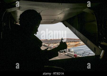 Einen Flug crewmember gibt das ok Zeichen der Pilot einer MV-22 Osprey, wie es startet von der Flight Deck von Wasp-Klasse amphibisches Schiff USS Kearsarge (LHD3). Kearsarge ist in die USA 5 Flotte Bereich der Maßnahmen zur Unterstützung der Marine im Einsatz für die Stabilität und Sicherheit in der Region zu gewährleisten und verbindet das Mittelmeer und den Pazifischen Raum durch den westlichen Indischen Ozean und drei strategischen Punkten ersticken. Stockfoto