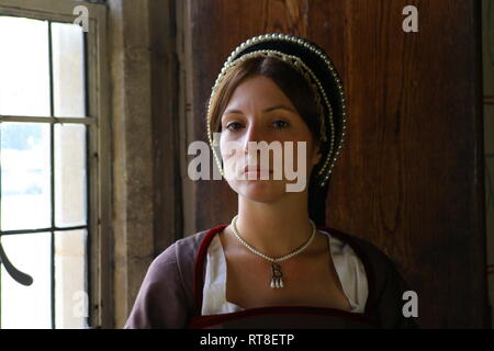 Eine schöne junge Frau gekleidet, wie Anne Boleyn durch ein Fenster im Tower von London sitzt und sieht nachdenklich aus. Stockfoto