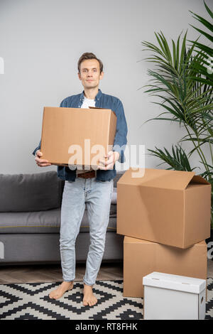 In voller Länge Foto von Mann mit Karton in Händen. Stockfoto