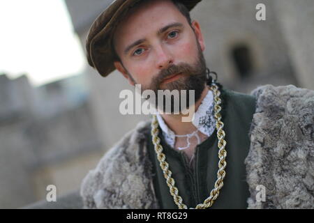 Portrait einer jungen Tudor Mann mit authentischen Tudor Kleidung Posen mit dem Tower von London im Hintergrund - er trägt reiche Kleider und gold Stockfoto