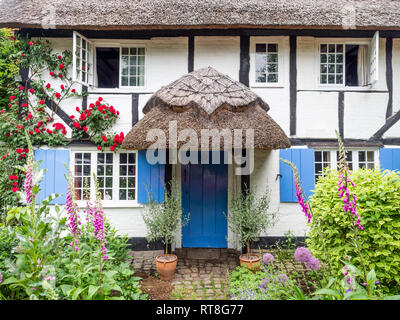 Eine fundamentale Chocolate Box Postkarte typischen reetgedeckten alten Tudor Jacobean Englisch Ferienhaus mit Garten in voller Blüte Stockfoto