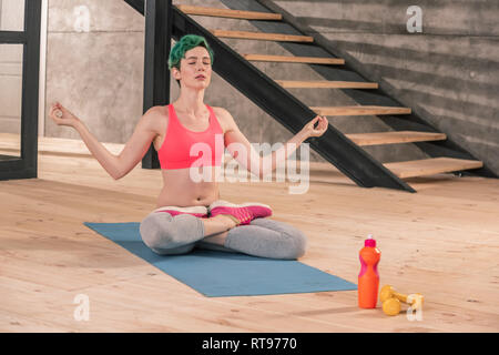 Grün - behaarte Frau Meditation sitzend auf blaue Sport mat Stockfoto