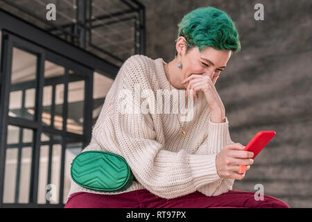 Frau lachend nach dem Lesen lustige Geschichte auf dem Smartphone Stockfoto