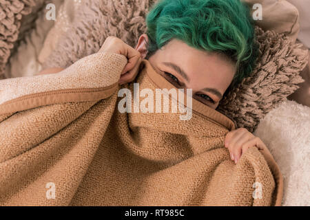 Grün - behaarte Frau ihr Gesicht verstecken hinter Plaid im Bett liegend Stockfoto