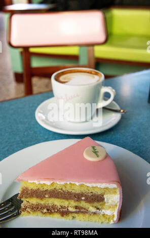 Cappuccino, Torta Rosa und mit pastellfarbenen Möbeln an der Bar Luce, Wes Anderson inspirierte Bar und Cafe in der Fondazione Prada in Mailand, Italien Stockfoto