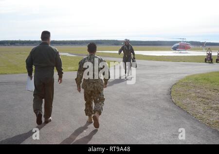 Hintere Adm. Bette Bolivar, Commander, Marine Region Südosten, und Naval Air Station Kalktünche-feld Executive Officer, Cmdr. Jim Brownlee zu Fuß aus dem kommandierenden Offizier zu grüßen, NAS Kalktünche-Feld, Kapitän Paul Bowdich, nach der Landung am neuesten abgelegenen Bereich der Marine. Bowdich dann weg von der Ribbon Cutting Veranstaltung für eine Masse von ungefähr 85 Personen die Eröffnung des Feldes für die Flugausbildung Operationen zu gedenken. Stockfoto