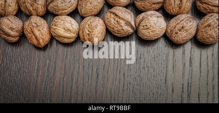 Blick von oben auf die ganze Walnüsse auf einem dunklen Holztisch, Platz für Text. Gesunde Ernährung Konzept. Stockfoto