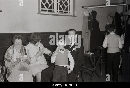 1950er Jahre, eine Familie auf eine Hochzeit in einer Kirche Halle genießen Eistüten und ein Getränk, England, Großbritannien sitzen. Stockfoto