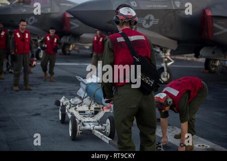 Marines mit der F-35 B Blitz II Loslösung von mittlerer Marine Tiltrotor Squadron 262 (Verstärkt) die Bombe Bucht einer F-35B Kämpfer für ein inertes vorbereiten Guided bomb Unit auf dem Flight Deck an Bord der Amphibisches Schiff USS Wasp (LL 1), Philippine Sea, Jan. 26, 2019. Die F-35 B wird eine Reihe von Waffen, darunter geführte Bomben und Raketen - Die multirole Fighter ist das Marine Corps' neuesten, Angriff jet und ist für Navy-Marine Corps amphibische Operationen gebaut. Die 31. MEU, das Marine Corps' nur kontinuierlich vorwärts - bereitgestellt MEU partnering mit dem Wasp Amphibi Stockfoto