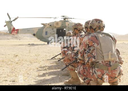 Eine Gruppe der omanischen Truppen kniet in der Bereitschaftsposition vor taktisch an Bord eines NH-90 Hubschrauber. Die US-Armee und der königlichen Armee des Oman sind die Durchführung von side-by-side Ausbildung während der Übung Inferno Creek 19. Die beiden Armeen, zusammen mit der Royal Air Force von Oman, Last- und geprobt Air Assault Taktiken in Rabkoot, Oman, Jan. 27, 2019 durchgeführt. Die bilaterale Übung wurde entwickelt, um die Beziehungen zwischen den Armeen zu stärken. Es ist eine Chance für beide Armeen taktische Kenntnisse und Verständnis für die jeweils anderen Kräfte und die Unterstützung langfristiger regionaler gemäßigtem zu bauen Stockfoto