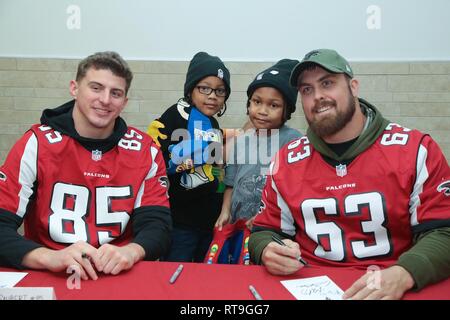 FORT Benning, Ga (Jan. 29, 2019) Atlanta Falcons tight end Eric Saubert, weit gelassen und offensive guard Ben Girlande, ganz rechts, geben Autogramme und posieren mit Fans während der NFL Gruß zum Service bei Mc Ginnis-Wickham Hall, Fort Benning, Georgia, Jan. 29, 2019. Die NFL und USO kamen zusammen, um die Veranstaltung, inklusive einem Treffen mit Atlanta Falcons Spielern und Cheerleadern, am Fort Benning, wo zwei Familien Tickets für das 2019 Super Bowl gewonnen zu werfen. Stockfoto