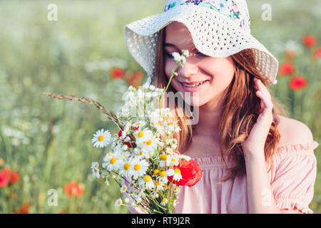 Beautieful junge Mädchen im Bereich der wilden Blumen. Jugendmädchen Ernte der Blumen auf der Wiese, holding Blumenstrauß. Sie trägt Hut Stockfoto