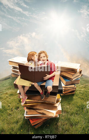 Kleines Mädchen und junge sitzt auf dem Turm aus großen Bücher. Kindheitsträume, kreative und Bildung Konzept. Fragen Welt. Abstrakte collage Stockfoto