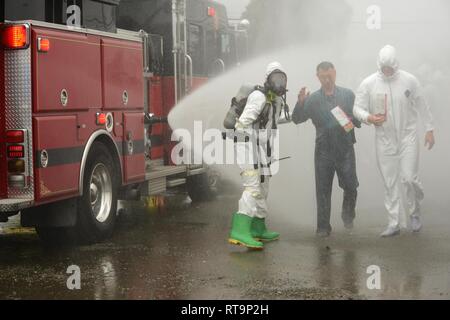 Mitglieder der Richmond, Kalifornien Feuerwehr Escort und simulierte Unfälle durch einen Brand Schlauch helfen versprühten chemischen Dekontamination Workstation während der Bay Area Übung, in Richmond, Kalifornien, 31.01.2019. Nationalen Schutz zivilen Support Teams arbeiteten mit lokalen Agenturen in einer Reihe simulierter chemische Vorfälle rund um die San Francisco Bay Area als Teil der BAYEX, eine Woche-lange Übung, die mehrere Antwort Agenturen zusammen zu bringen Interoperabilität bei großen Katastrophen zu verbessern. (National Guard Stockfoto