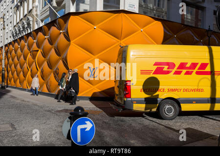 Ein DHL Lieferung Kurier van Antriebe hinter den temporären Renovierung Horten der Luxusmarke Louis Vuitton in New Bond Street, am 25. Februar 2019 in London, England. Stockfoto