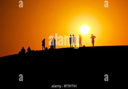Ein schönes Bild von Menschen warten auf den Sonnenuntergang am Rand der Düne (Rot Sand dune) mit orange Himmel Hintergrund im Sommer in Mui Ne, Vietnam Stockfoto