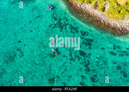 Ansicht von oben, beeindruckende Luftaufnahme von drei traditionellen Long-tail Boote schwimmend auf einem Türkis und klares Meer, Maya Bay, Thailand. Stockfoto