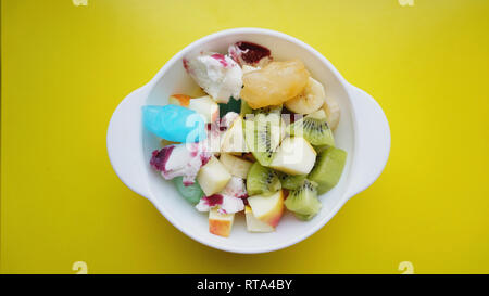In der Nähe der Wüste mit frischem Obst und Eis. Gemischte Früchte mit mit Obst Eis auf gelbem Hintergrund Stockfoto