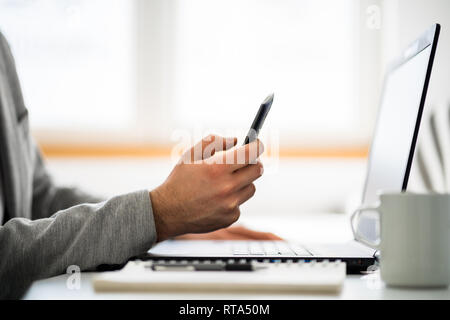 Unternehmer ist das Arbeiten im Büro. Er ist mit Smartphone. Stockfoto