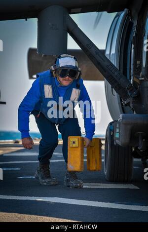 ARABIAN GULF (Feb. 4, 2019) Bootsmann Mate 3. Klasse Kyle Houchens entfernt Unterlegkeile von Ein UH-60 Black Hawk Hubschrauber, zu Task Force Javelin zugeordnet, auf dem Flugdeck der Arleigh-Burke-Klasse geführte Anti-raketen-Zerstörer USS Mitscher (DDG57). Mitscher ist in die USA 5 Flotte Bereich der Maßnahmen zur Unterstützung der Marine im Einsatz für die Stabilität und Sicherheit in der Region zu gewährleisten und verbindet das Mittelmeer und den Pazifischen Raum durch den westlichen Indischen Ozean und drei strategischen Punkten ersticken. Stockfoto