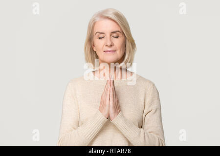 Dankbar, glücklich, reife Frau meditieren Beten auf Hintergrund isoliert Stockfoto