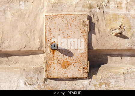 Rostiges Metall Tür des Schaltschranks. Alten, verlassenen elektrische Anschlusskasten auf der Mauer eines alten Hauses. Stockfoto