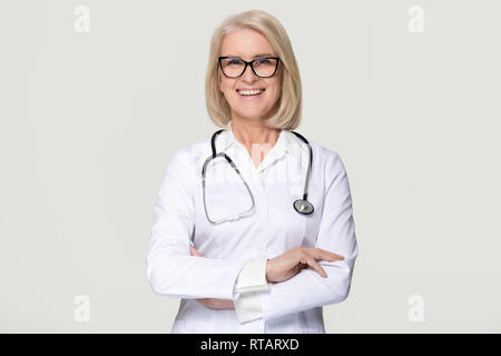 Gerne reife Frau Doktor Portrait auf grauem Hintergrund Stockfoto