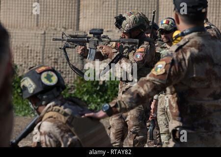 Eine irakische Terrorismusbekämpfung Service Basic-Kurs (BLC) Student feuert seine Waffe wie seine Ausbilder während einer Reihe statt Treffsicherheit Fähigkeiten in der Nähe von Bagdad, Irak, Feb 4, 2019 schärfen. BLC ist von irakischen Ausbilder mit Hilfe von Alliierten Streitkräften geführt und bereitet Soldaten CTS Soldaten, führende Rollen im Team und Gruppe das Niveau von Führungskompetenzen, Ausbildung, und warfighting Konzepte und Fähigkeiten. Die Koalition wird die Arbeit von, mit und durch die irakischen Sicherheitskräfte die Bedingungen für die Stabilität in der Region zu setzen und das Wiederaufleben von ISIS zu verhindern. Stockfoto