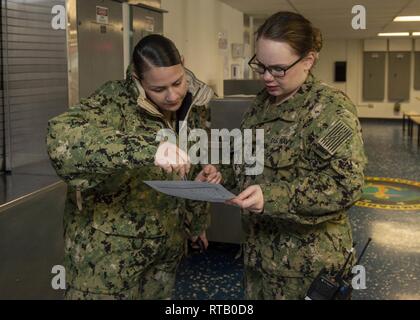 SAN DIEGO (Feb. 5, 2019) Quartermaster 1. Klasse Joshayra Verafeliciano, links, von Tampa, Fla., und Lt. j.g. Sarah Platt, von Sandpoint, Idaho, sowohl der Amphibisches Schiff USS BONHOMME RICHARD (LHD 6), überprüfen Sie die Regeln der Probefahrt auf das Chaos decks Der barge zum Schiff zugewiesen. Unteroffiziere die Prüfung machen, die gute Kenntnisse in Navigation regeln wie korrekte Schiff manövrieren sowie optische und akustische Signale auf See eingesetzt zu behalten. Bonhomme Richard ist in seinen Heimathafen San Diego. Stockfoto