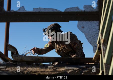 Eine irakische Terrorismusbekämpfung Service Basic Leader Kurs student kommuniziert mit seinem Team, wie sie eine taktische Bewegung ein Ziel der Schulung in der Nähe von Bagdad, Irak, Feb 5, 2019 zu löschen. BLC lehrt und Nachwuchsführungskräfte die Fähigkeiten und die Maßnahmen, die erforderlich sind, um Ihre individuellen Führungsfähigkeiten zu entwickeln. Streitkräfte der Koalition beraten und den irakischen Ausbilder in einer gemeinsamen Anstrengung eine Elite zu bauen helfen, sich selbst tragende Kraft, der Irak souveränen Grenzen sichern kann, zum Schutz der Bevölkerung und der dauerhaften Niederlage von ISIS gewährleisten. Stockfoto