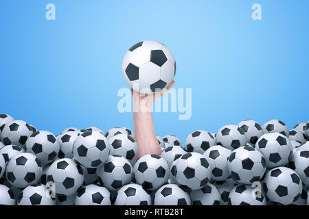 Die Hand, die sich aus unten eine Menge Fußbälle und halten einen Fußball. Stockfoto