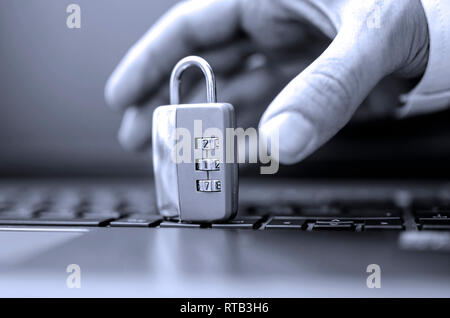 Detail der Hacker Hand stehlen Vorhängeschloss vom Laptop Tastatur. Konzept der Computerkriminalität. Stockfoto