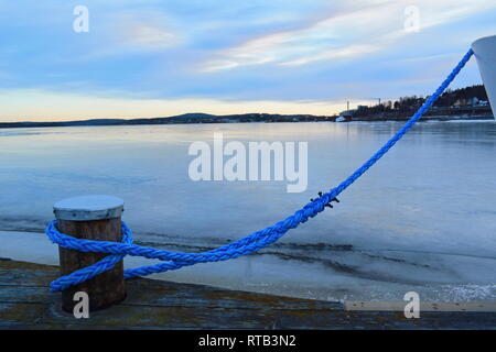 Nahaufnahme von einem blauen Seil Verankerung ein Schiff in einem Hafen Bucht Eis bedeckt. Stockfoto