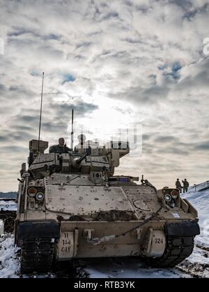 U.S. Army Staff Sgt. Daniel Agriesti, die Kavallerie Scout mit der 1. Staffel, 4 U.S. Cavalry Regiment in Fort Riley, Kansas, erläutert die Funktionen des M2 Bradley fighting Fahrzeug zu Vincent 'B.J.' Lawrence, der Oberbefehlshaber der Kriegsveteranen der USA, vor einem live-fire Übung an einem Schießplatz in der Nähe von Świętoszów, Polen, Feb 6, 2019. Als Kommandant der VFW, Lawrence persönlich die Soldaten der 1-4 Kavallerie besucht, als in einer Bemühung, besser die Ausbildung Umwelt verstehen mobilisiert und die Lebensbedingungen der Truppen in Übersee, in Unterstützung stationiert Stockfoto