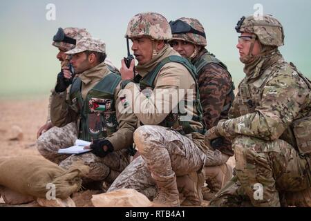 Ein Jordanien Streitkräfte Kompaniechef der 5. Grenze Wache Bataillon gibt Befehle an seine Soldaten während Staff Sgt. John S. Rotner (rechts) wirkt als Beobachter, Controller, Trainer (ÜLG), die während einer Live-fire Übung an einem Schießplatz außerhalb von Amman, Jordanien, Feb 6, 2019. Rotner ist ein Kalifornien Army National Guard Soldat mit Bravo Truppe, 1.Staffel, 18 Cavalry Regiment, das Training mit JAF Bundesgrenzschutz Kräfte als Teil des Jordan operativen Engagement Program sind. (Army National Guard Stockfoto