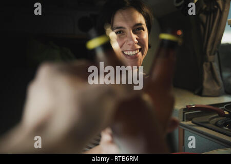 Junge brunette Froehlich pauke Flaschen mit menschlicher Nähe Elektroherd in Mobile home Stockfoto
