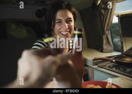 Junge brunette Froehlich pauke Flaschen mit menschlicher Nähe Elektroherd in Mobile home Stockfoto