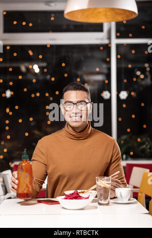 Vertikale Portrait von Kerl, dem die Kellner bringen köstliches Drei-Gang-Menü, während er die Flasche. Stockfoto