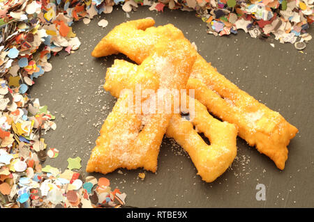Stapel von Italienischen frittiertes Gebäck, hausgemachtes für Karneval Feier auf schiefer Platte whit farbige Konfetti Stockfoto