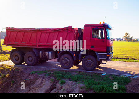 Eine rote Dump Truck für Sand Lieferung erfolgt mit Feld- und Himmel im Hintergrund geparkt Stockfoto