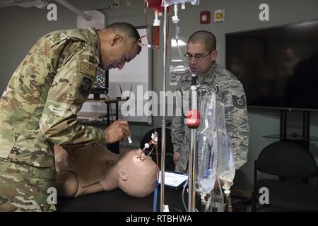 Us Air Force Chief Master Sgt. Terrence Greene, Befehl Chef des Air Mobility Command, Scott Air Force Base, Illinois, prüft die Schülerinnen und Schüler auf "Trauma Hal" Feb 7, 2019, in Dover Air Force Base, Del Tech Sgt. Juan Davila, Luft- und Raumfahrt Medizin 436th Squadron medizinische und Operations Techniker, demonstriert die Schulungen des Traumas Hal während Greene's Besuch der 436th Medical Group. Stockfoto