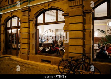 Straßburg, Frankreich - 21 November, 2017: Touristen und Einheimische trinken einen warmen Kaffee oder Tee in der Brent Cafe in Straßburg - Blick von der Straße bei Nacht Stockfoto