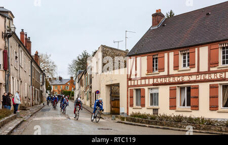 Dampierre-en-Yvelines, Frankreich - 4. März 2018: Das Peloton aproaching auf einer kleinen traditionellen Straße in einem französischen Dorf bei Paris-nizza 2018. Stockfoto