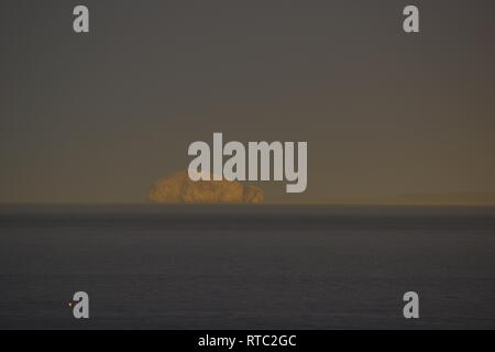 Der Bass Rock, vulkanische Plug Insel und Gannet Kolonie, in der äußeren Firth von weiter im goldenen Licht an einem Sommerabend bei einem regen Sturm. UK. Stockfoto