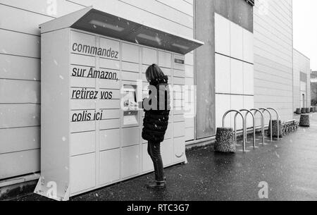 Straßburg, Frankreich - Feb 8, 2018: Seitenansicht des junge Frau mit Amazon Spind die Self-service-Paketdienst Station in der Nähe von Auchan Supermarkt Stockfoto